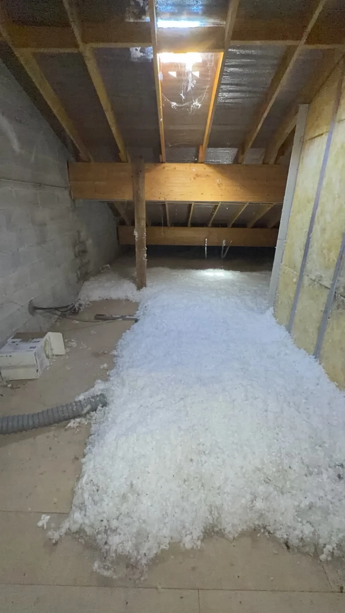 Tas d’isolant blanc en cours de soufflage dans les combles de l’établissement